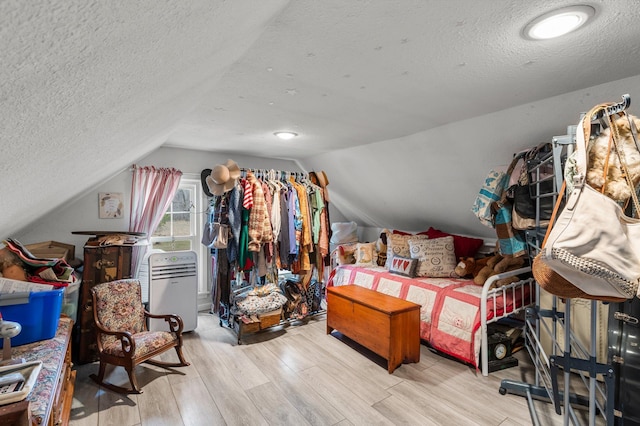 bedroom featuring lofted ceiling, wood finished floors, and a textured ceiling