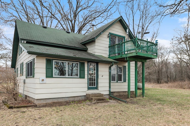 view of front of home with a front lawn, roof with shingles, a wooden deck, and entry steps