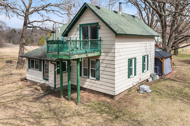 exterior space featuring a deck, roof with shingles, and a lawn