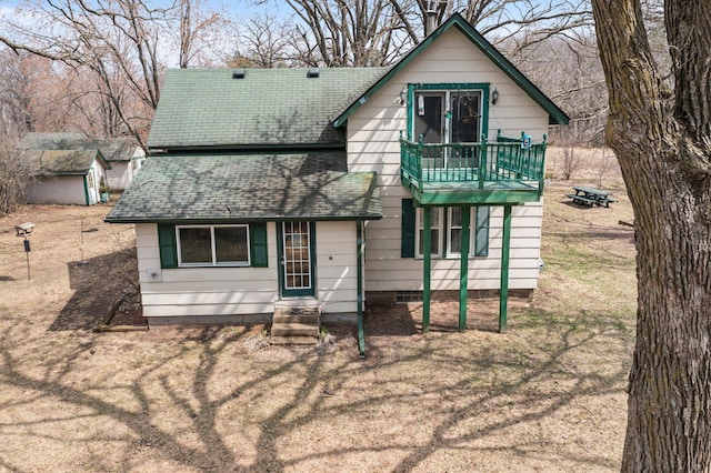 view of front facade featuring roof with shingles and a balcony