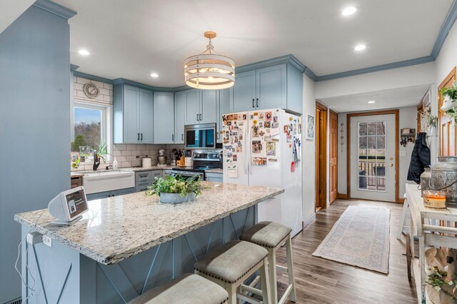 2908 River Rd, Saint Croix Falls, WI 54024 - kitchen featuring stainless steel appliances, a sink, a breakfast bar, wood finished floors, and decorative backsplash