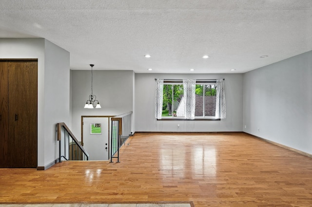11560 Red Fox Dr, Maple Grove, MN 55369 - unfurnished living room featuring wood finished floors, a textured ceiling, baseboards, a chandelier, and recessed lighting