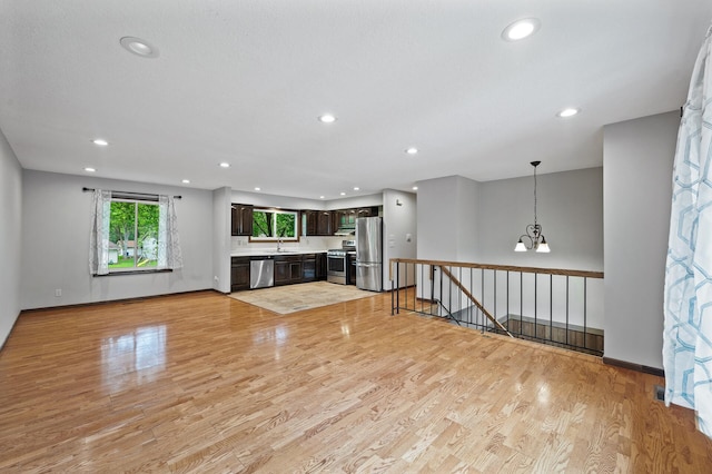 11560 Red Fox Dr, Maple Grove, MN 55369 - unfurnished living room featuring light wood-type flooring, recessed lighting, a chandelier, baseboards, and a sink