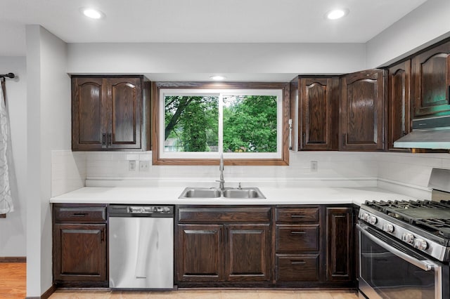 11560 Red Fox Dr, Maple Grove, MN 55369 - kitchen featuring stainless steel appliances, a sink, under cabinet range hood, dark brown cabinets, and light countertops
