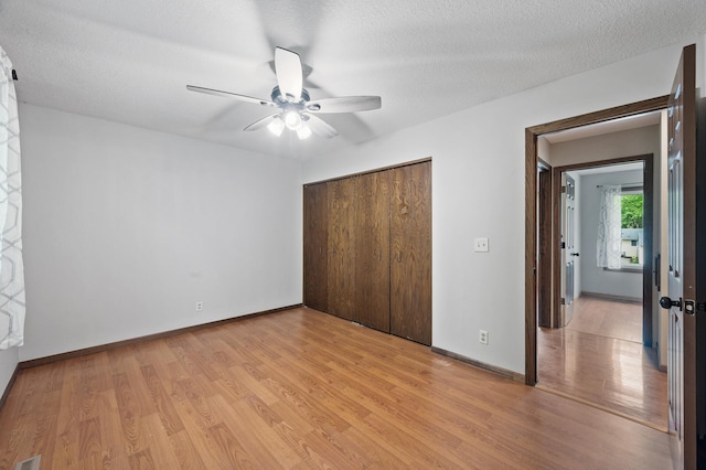 11560 Red Fox Dr, Maple Grove, MN 55369 - unfurnished bedroom with light wood-type flooring, a closet, baseboards, ceiling fan, and a textured ceiling