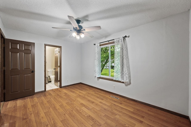 11560 Red Fox Dr, Maple Grove, MN 55369 - unfurnished bedroom with light wood-style flooring, baseboards, a textured ceiling, ensuite bath, and ceiling fan