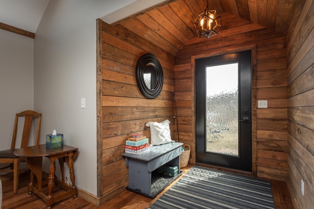 doorway to outside featuring wood finished floors, baseboards, lofted ceiling, and a healthy amount of sunlight