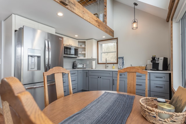 kitchen featuring pendant lighting, appliances with stainless steel finishes, a sink, light countertops, and white cabinetry