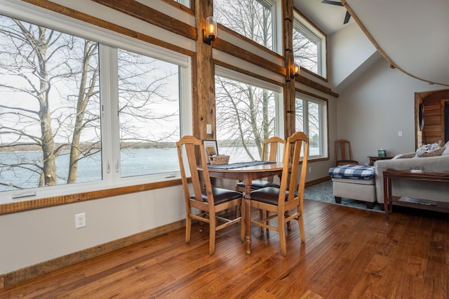 dining area with a water view, baseboards, vaulted ceiling, and hardwood / wood-style floors
