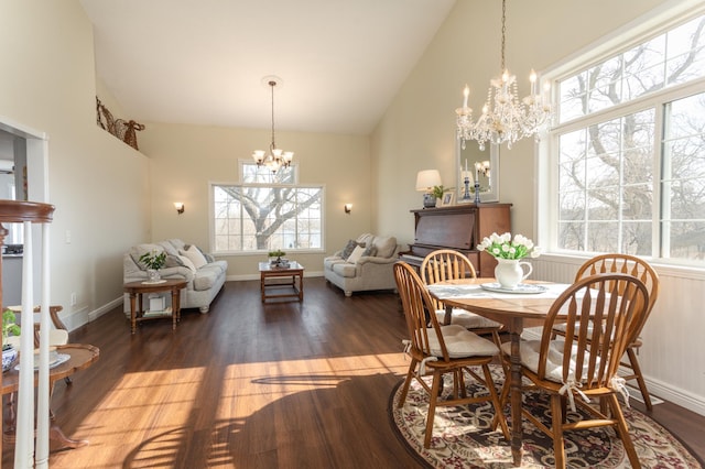 dining room with an inviting chandelier, baseboards, wood finished floors, and high vaulted ceiling