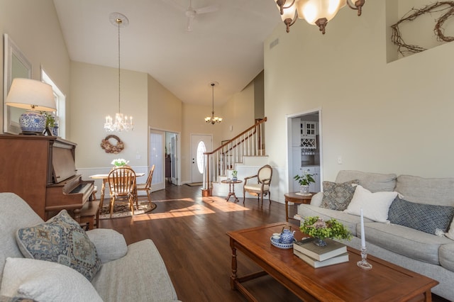 living area featuring an inviting chandelier, visible vents, wood finished floors, high vaulted ceiling, and stairway