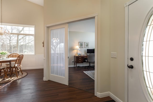 entrance foyer with dark wood-style floors and a wainscoted wall