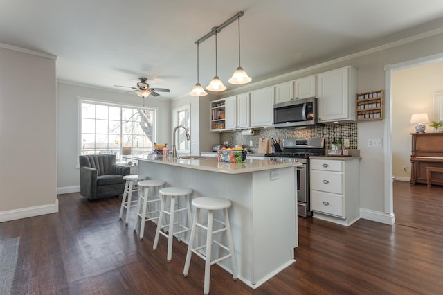 kitchen featuring ornamental molding, dark wood-style floors, white cabinetry, tasteful backsplash, and stainless steel appliances