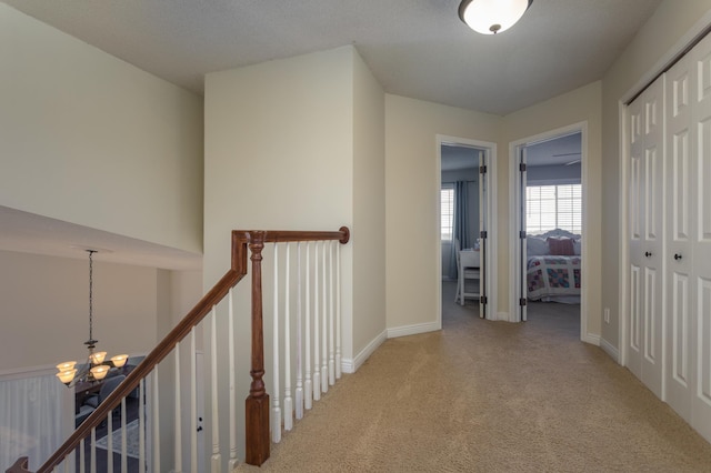 hallway with baseboards, a notable chandelier, and carpet