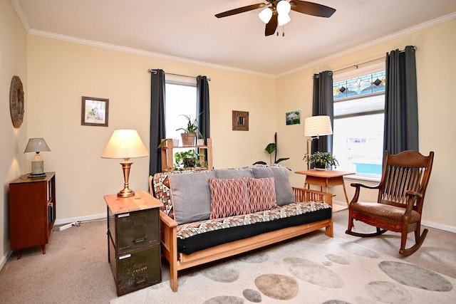 carpeted living room featuring a ceiling fan, baseboards, a healthy amount of sunlight, and crown molding