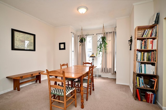dining room with baseboards, light colored carpet, and crown molding