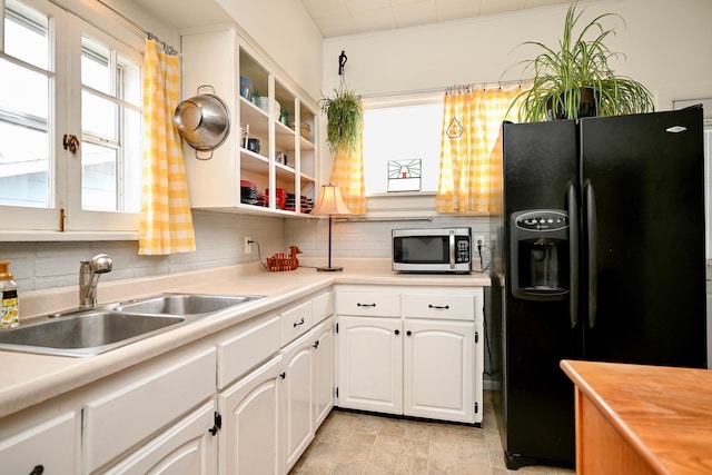 kitchen featuring stainless steel microwave, backsplash, a sink, and black fridge