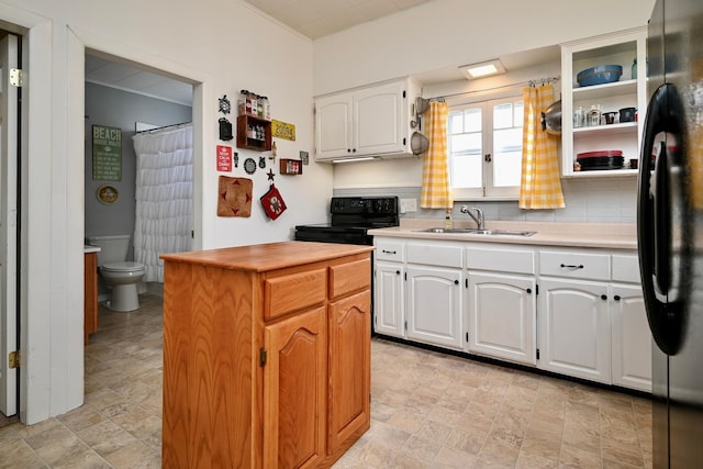 kitchen with white cabinets, a sink, a kitchen island, stone finish flooring, and black appliances
