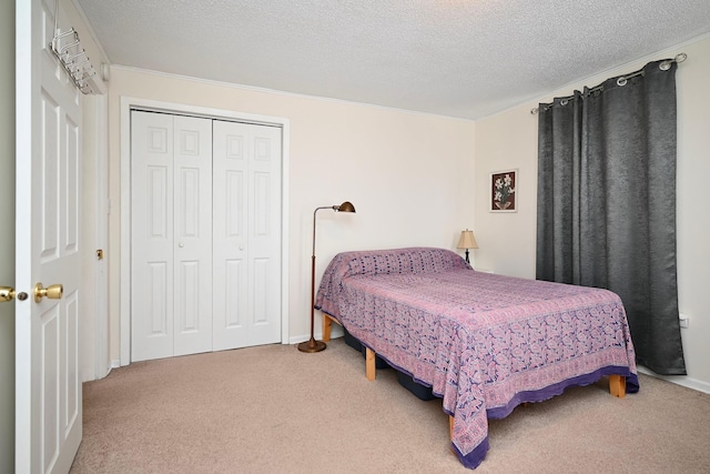 bedroom with a textured ceiling, baseboards, carpet, a closet, and ornamental molding