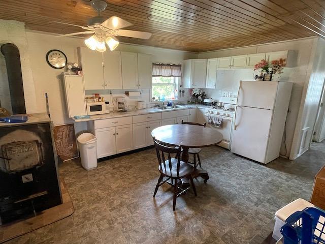 kitchen with white cabinetry, a sink, white appliances, wood ceiling, and ceiling fan