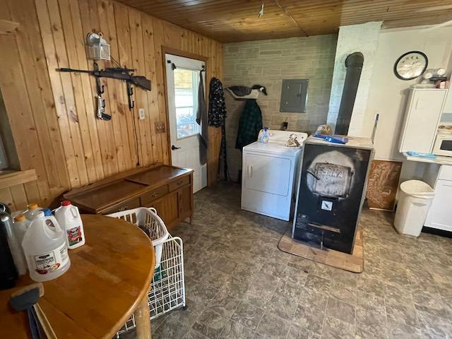 laundry area with wood walls, laundry area, a wood stove, wooden ceiling, and washer / dryer