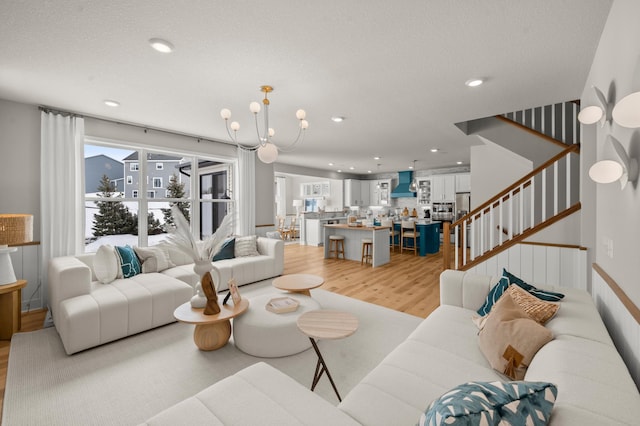 living area featuring stairway, a chandelier, light wood finished floors, and recessed lighting