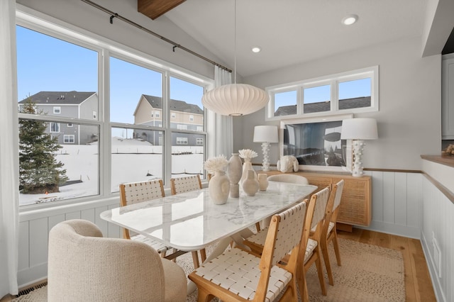 dining room featuring lofted ceiling, visible vents, light wood finished floors, and a wainscoted wall