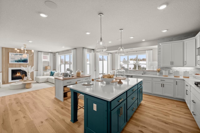 kitchen featuring open floor plan, a textured ceiling, light wood-type flooring, and light countertops