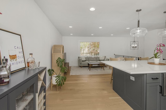 kitchen featuring light wood-style floors, light countertops, gray cabinets, pendant lighting, and a breakfast bar area