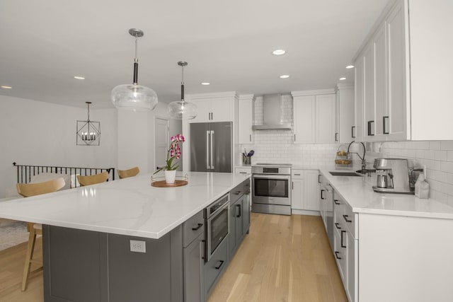 kitchen featuring high quality fridge, wall chimney range hood, stove, a kitchen breakfast bar, and white cabinets
