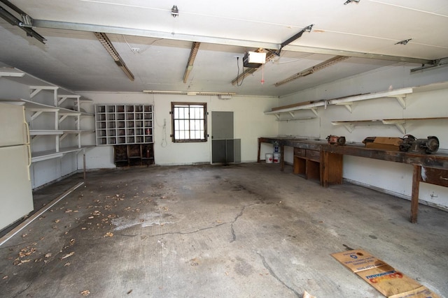 garage with a garage door opener, freestanding refrigerator, and a workshop area