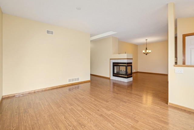 7931 Pinnacle Ave NE, Otsego, MN 55330 - unfurnished living room featuring light wood-style flooring, a multi sided fireplace, and a chandelier