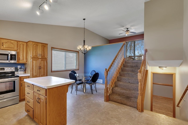 kitchen featuring pendant lighting, appliances with stainless steel finishes, light countertops, ceiling fan with notable chandelier, and lofted ceiling