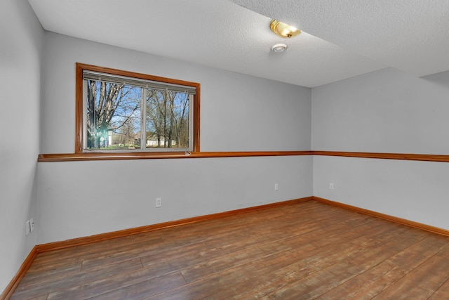 unfurnished room featuring a textured ceiling, baseboards, and hardwood / wood-style floors