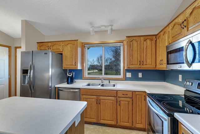 kitchen with light countertops, a textured ceiling, appliances with stainless steel finishes, and a sink