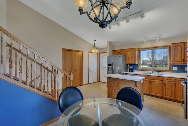 kitchen featuring light countertops, a sink, a kitchen island, and stainless steel fridge with ice dispenser