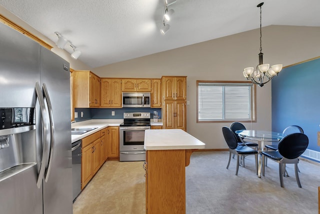 kitchen featuring light countertops, rail lighting, appliances with stainless steel finishes, and lofted ceiling