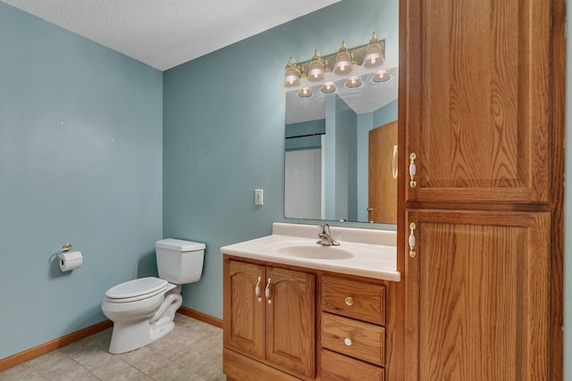 bathroom featuring toilet, baseboards, a textured ceiling, and vanity