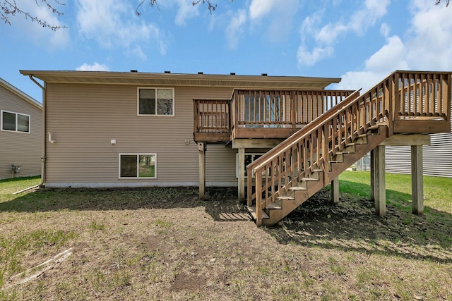 back of property with a lawn, a wooden deck, and stairway