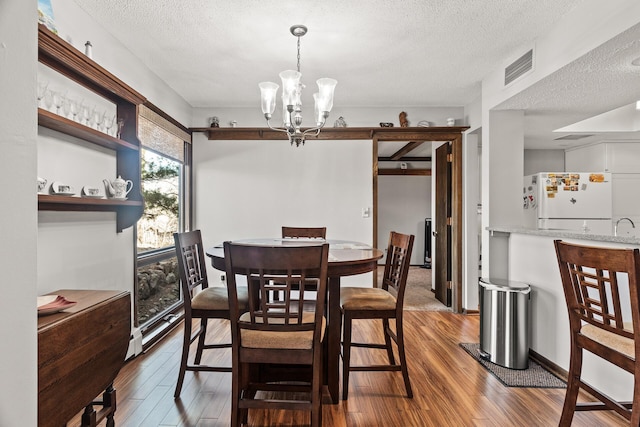 6085 Lincoln Dr Unit 122, Edina, MN 55436 - dining area featuring a textured ceiling, wood finished floors, visible vents, and an inviting chandelier