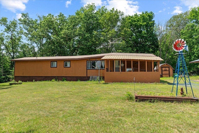 view of front of home with a storage unit, an outbuilding, metal roof, and a front lawn