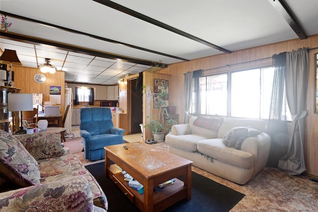 carpeted living area featuring wood walls and beam ceiling
