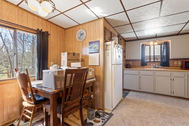 dining room with wooden walls, plenty of natural light, and light carpet
