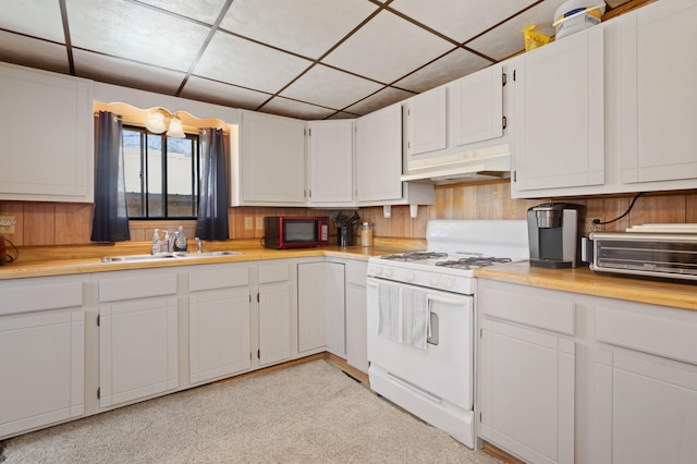 kitchen featuring a toaster, white gas stove, a paneled ceiling, under cabinet range hood, and a sink