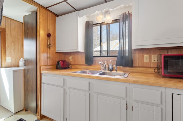 kitchen featuring wooden walls, white cabinets, a sink, and a toaster