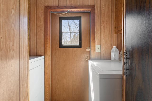 laundry room featuring wooden walls, laundry area, and washing machine and dryer