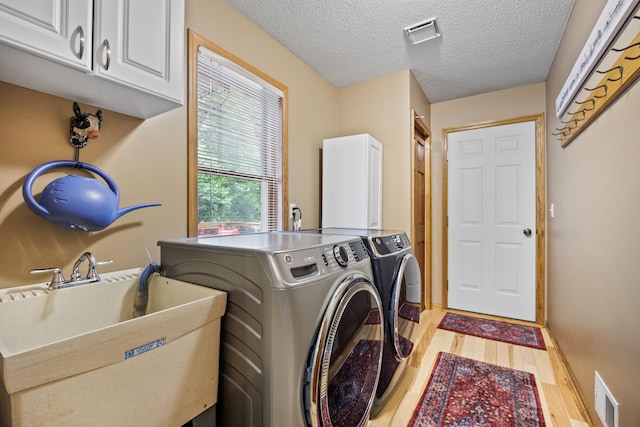 4545 Terraceview Ln N, Plymouth, MN 55446 - laundry room with cabinet space, washer and clothes dryer, light wood-style floors, and a textured ceiling