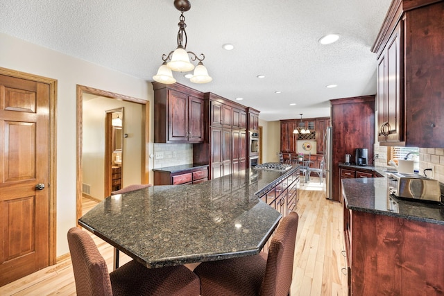 4545 Terraceview Ln N, Plymouth, MN 55446 - kitchen featuring a chandelier, a large island, appliances with stainless steel finishes, a textured ceiling, and tasteful backsplash