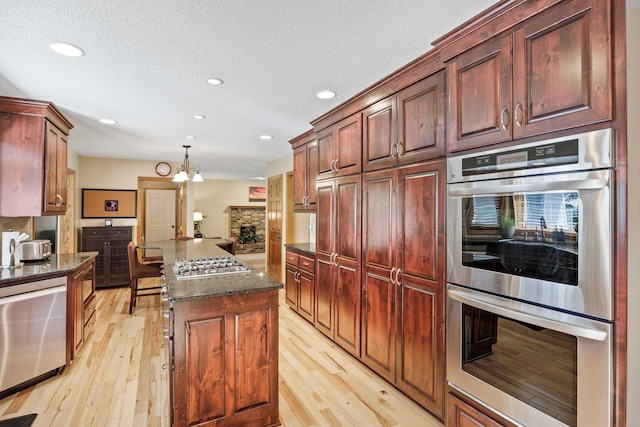 4545 Terraceview Ln N, Plymouth, MN 55446 - kitchen with stainless steel appliances, light wood-style floors, recessed lighting, a kitchen island, and dark stone countertops