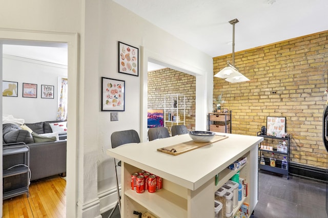 dining area featuring brick wall and wood finished floors